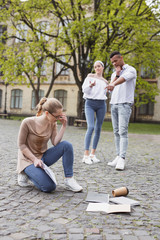 Fototapeta premium Insulting students. Two insulting students abusing their fellow student dropping her things on the ground