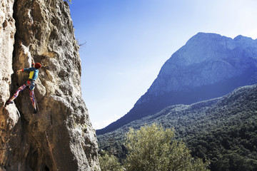 Woman rock climber. Rock climber climbs on a rocky wall. Woman makes hard move.