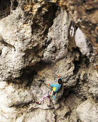 Woman rock climber. Rock climber climbs on a rocky wall. Woman makes hard move.