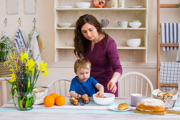 Child helping mother make cookies in modern kitchen. Mother and son cooking