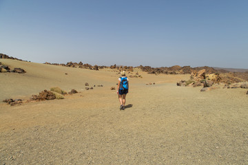 Fototapeta na wymiar Journey in the desert. Walking hiking stone desert trail dirt road towards mountains. Walking alone in the desert. 
