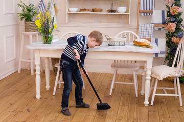 Child cleaning room with broom. Child cleaning kitchen.