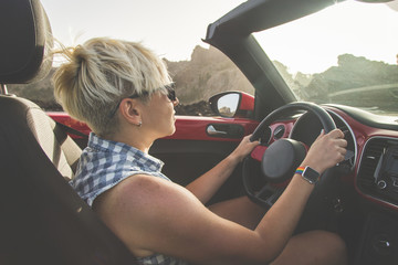 The girl driving a car. Portrait of Young girl driving cabriolet at sunset.