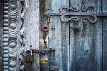 Old wooden gate closed on rusty padlock, texture