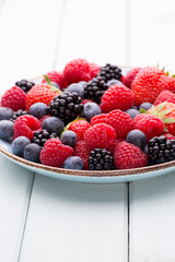 Fresh berry salad on blue dishes. Vintage wooden background.