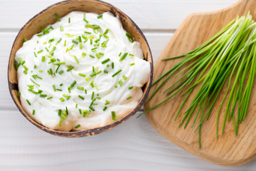 Bowl of cream cheese with green onions, dip sauce on wooden table.