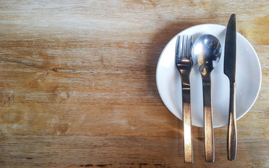 Empty dish with spoon and knife on wooden table near the window