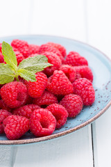 Fresh raspberries in a plate on a  vintage background.