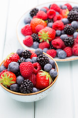 Fresh berry salad on blue dishes. Vintage wooden background.