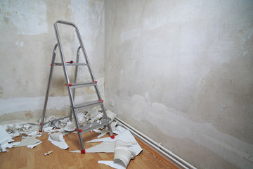 empty room with bare walls, ladder and old wallpaper scraps on floor during redecoration, diy home...