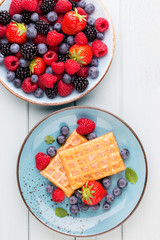 Fresh berry salad on blue dishes. Vintage wooden background.