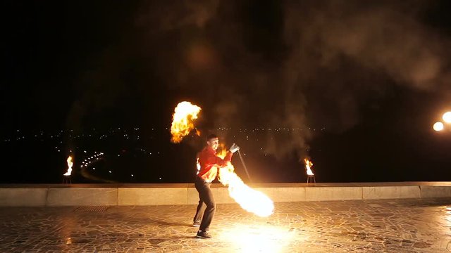 Artist man rotates the fireball.Man twist fiery circles on a fire show.Man does a fire performance.Fire show amazing at night.