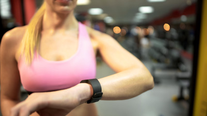 Fototapeta na wymiar Female looking at her smart watch before starting training in gym, fitness app