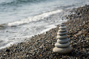 a pyramid of stones on a pebble beach on the background of the sea waves in the evening