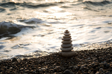perfect pyramid of stones against the background of the waves and the sunset