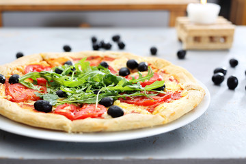 Pizza z pomidorami, rukola i czarnymi oliwkami.