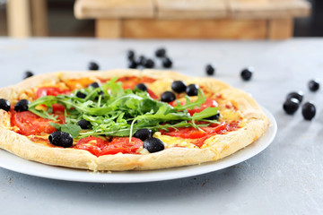 Włoska pizza. Pizza z pomidorami, czarnymi oliwkami, rukolą.