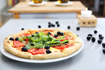 Pizza włoska. Pizza z pomidorami, czarnymi oliwkami, rukolą.