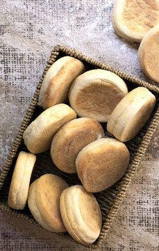 Rows of English muffins in a rectangular wicker basket.