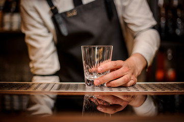 Bartender holding a beautiful oranate glass on the bar counter
