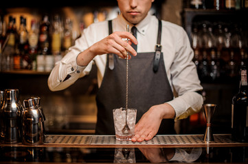 Bartender stirring ice in the ornate glass