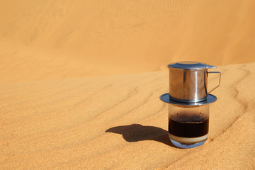 Drip Black Coffee in Vietnamese style with condensed milk on a red sand with copy space....