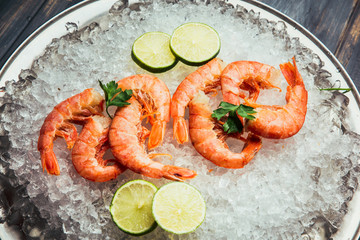 Shrimp with ice with lime and salad on the plate. On wooden background