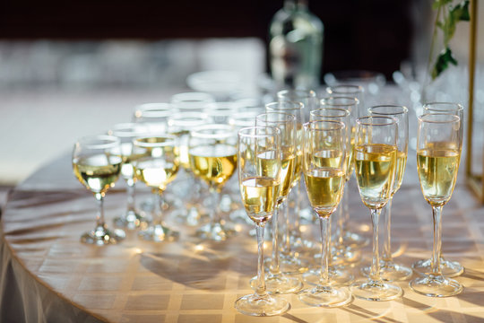 A lot of wine glasses with a cool delicious champagne or white wine at the bar. Alcohol background.