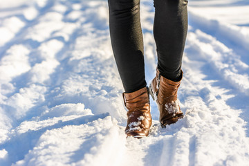 Woman walking in snow boots, winter womens shoes on the feet and legs dressed in leggings - obrazy, fototapety, plakaty