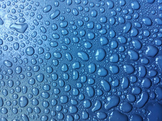 Large and small drops of water on a blue background. Texture, seamless background