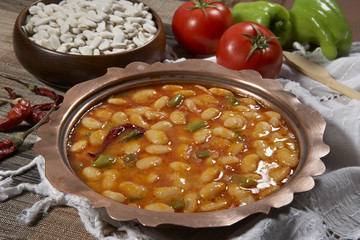 Dried beans,white beans in tomato sauce in a copper bowl closeup. horizontal
