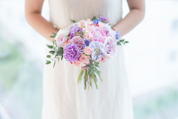 Obraz na płótnie Canvas A bridal bouquet in the hand. Fresh mixed flowers bouquet of pink peony, blue scabiosa, moonlight carnation, white spray roses, memory lane roses, violet waxflower, cornflower and eucalyptus