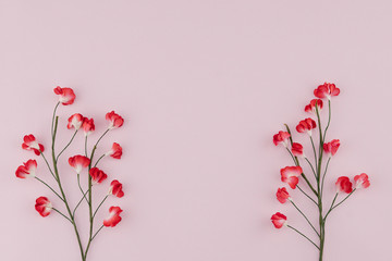 Red paper flowers with branch on pink background with copy space