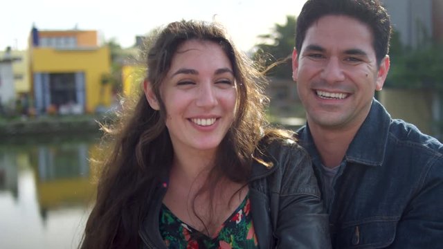 Closeup Of Man Giving His Girlfriend A Hug, He Makes A Funny Face And They Laugh, Venice Beach Canals, CA (Slow Motion)