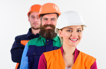Woman and men in hard hats stand close as team.