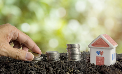 saving money to build a house concept, house and coins in soil