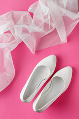 White wedding shoes on pink background