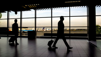 Fototapeta na wymiar Silhouettes of passengers walking at terminal hall, business trip, airport
