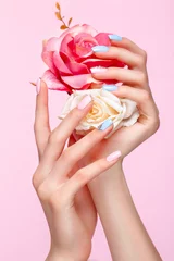  Mooie roze en blauwe manicure met kristallen aan de vrouwelijke kant. Detailopname. Foto genomen in de studio © Kobrinphoto