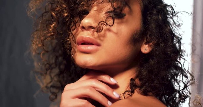 Face image of swarthy beautiful model with curly hair and cared skin. Beauty concept.