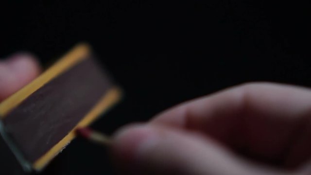 Close up of hands lighting a match.