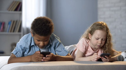 Little children addicted to mobile phones playing games with concentrated faces