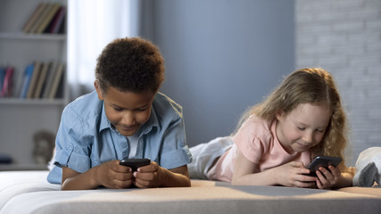 Fototapeta na wymiar Smiling kids playing online games in mobile application, addiction to gadgets
