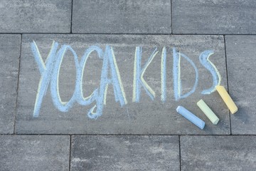 Yoga kids text written by children on the paving slab with colored crayons