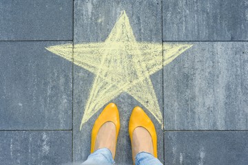 Drawing of crayons on the asphalt - star and feet of woman