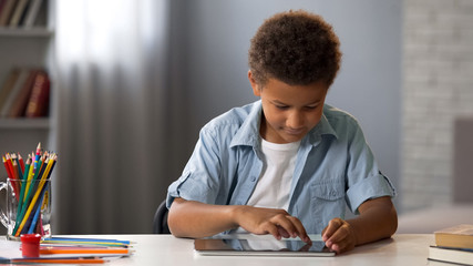 Naklejka premium Little clever kid swiping tablet playing in interactive educational application