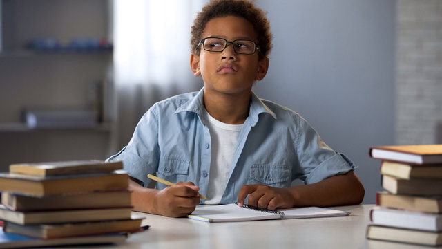 Afro-American boy thinking on school essay, smart kid doing homework, education