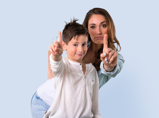 Mother and daughter counting number one sign on blue background