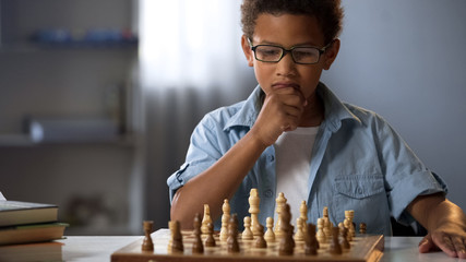 Little boy thinking on chess move, intelligent hobby, logic development, leisure