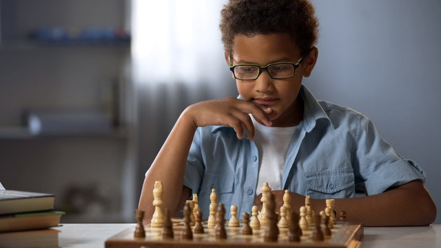 Concentrated boy developing chess strategy, playing board game with friend